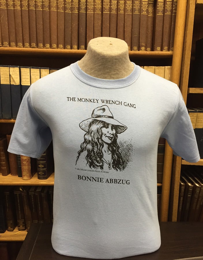 Item #49491 Bonnie Abbzug T-Shirt - Light Blue (S); The Monkey Wrench Gang T-Shirt Series. Edward Abbey/R. Crumb.
